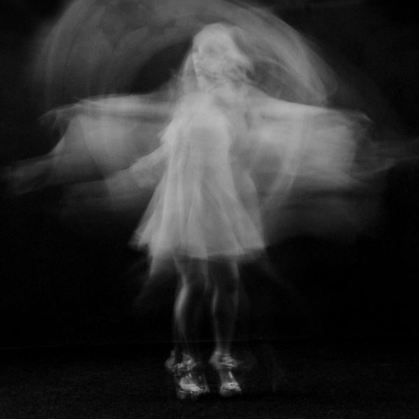 Person in a flowing yoga movement against a dark background.